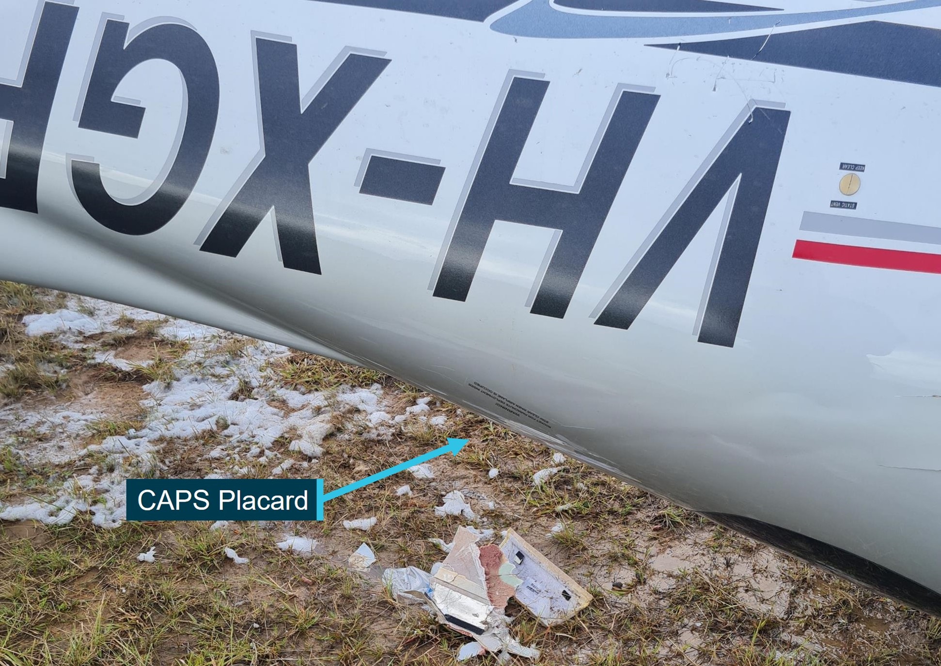 Wreckage (inverted) at accident site showing CAPS warning placard on left rear fuselage