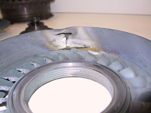 Second-stage NGV housing with a large puncture and cracking from the released turbine blade.