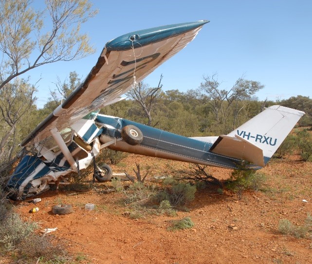 Photograph showing the accident site terrain and impact damage to the aircraft