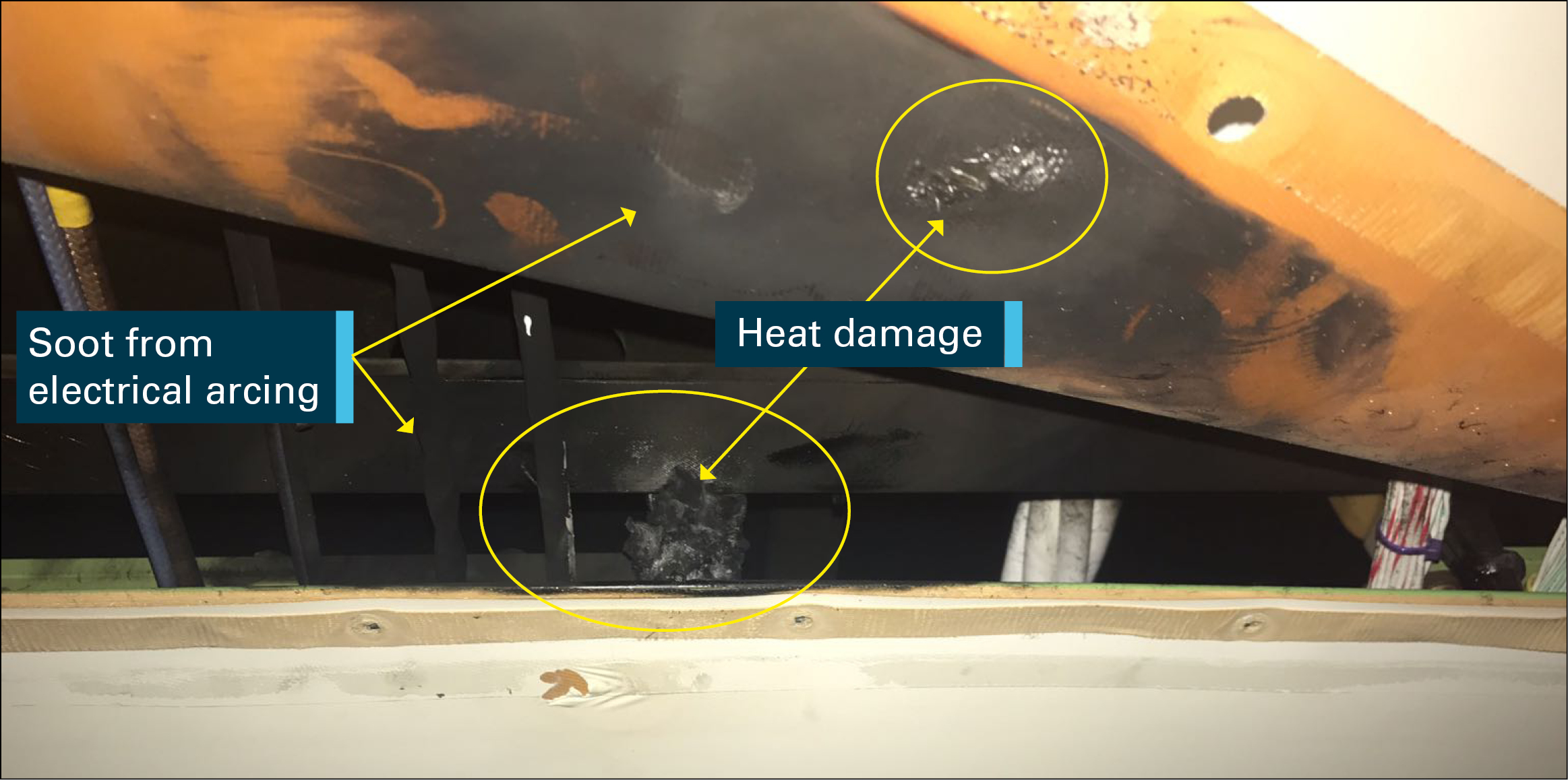 Figure 2: Damaged floor beams, webs and wiring covered in soot with ceiling panel opened. Source: Etihad Airways, modified by the ATSB