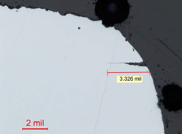 Figure 9: Metallographic cross section adjacent to the fracture surface showing secondary cracking. The micrograph shows the secondary cracking extending from the dowel pin hole in the region adjacent to the primary fracture surface. Also, note the corroded initial fracture surface at the top of the image, and the rounded fracture edge. Note that 2 mil is approximately equal to 50 µm. The crack length in the image is approximately 84 µm in length. Source: GE