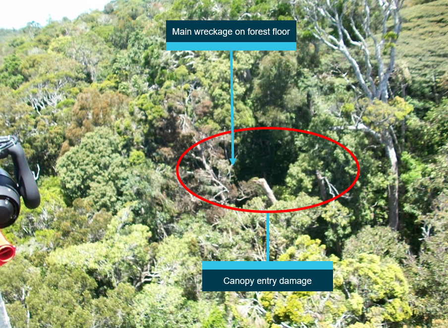 Figure 5: Approach to canopy entry directly above wreckage site. Rescue helicopter view of the damaged canopy. Main body of the helicopter is located on the forest floor, about 100 ft directly below the canopy damage.<br />
Source: Search and rescue helicopter service (courtesy Queensland Police Service), annotated by ATSB